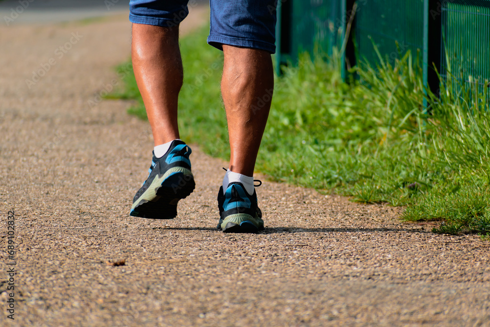 Man walking with sneakers on a path, close-up of his legs, sports activity, healthy lifetsyle