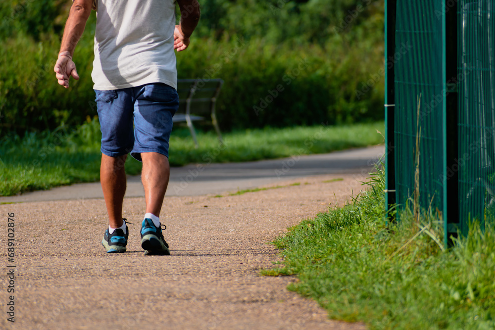 Man walking with sneakers on a path, close-up of his legs, sports activity, healthy lifetsyle Man walking with sneakers on a path, close-up of his legs, sports activity, healthy lifetsyle