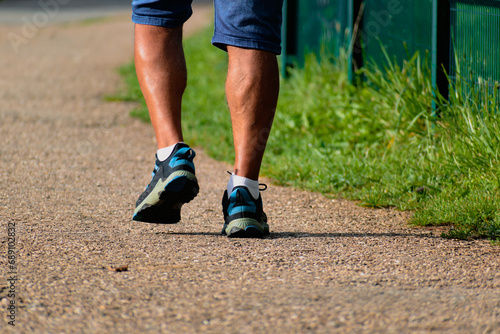 Man walking with sneakers on a path, close-up of his legs, sports activity, healthy lifetsyle