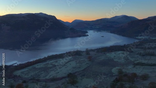 Rising through thin mist with dark lake surrounded by mountains prior to an autumnal sunrise. Ullswater, English Lake District, Cumbria, UK. photo