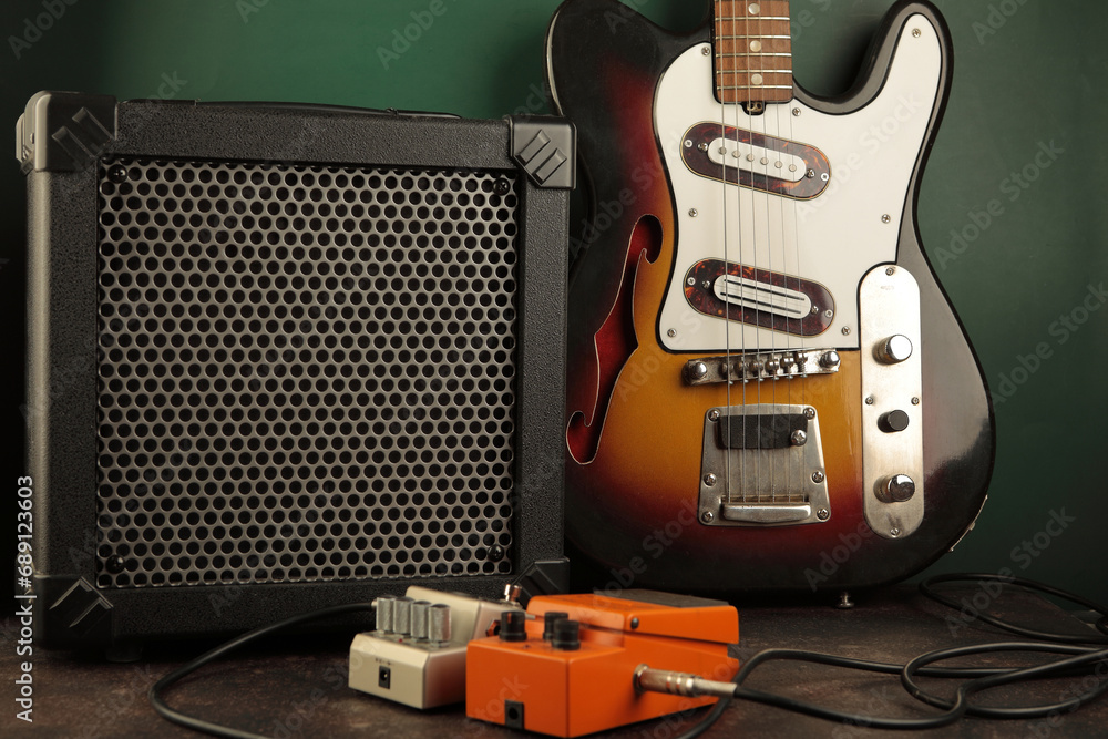Vintage electric guitar, guitar amplifier and effects pedals for the guitarist against a dark green wall. - obrazy, fototapety, plakaty 