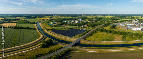 Panorama of solar panels at a sunny day between fields, river and a street. photo