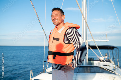 Mature man in a life jacket on a yach feeling good