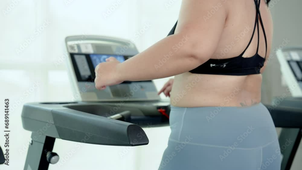 Close-up torso overweight woman wearing exercise clothes, for good workout, woman running on treadmill burns various part body, use hand adjust running level continuously, order maintain good balance. Close-up torso overweight woman wearing exercise clothes, for good workout, woman running on treadmill burns various part body, use hand adjust running level continuously, order maintain good balance.