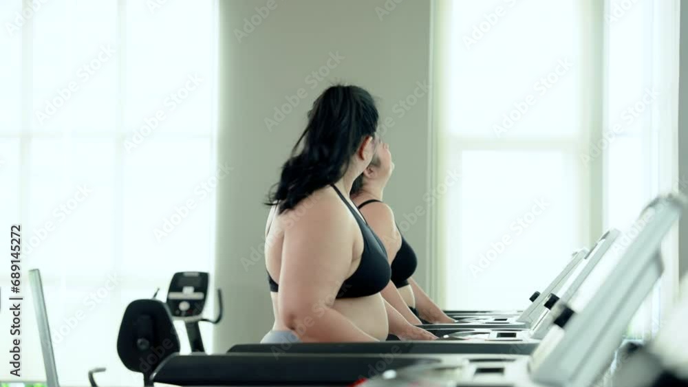 Two overweight Asian women wore exercise clothes, for good workout, two them started by walking for balance on track before starting off with light run, let's talking while walking. Two overweight Asian women wore exercise clothes, for good workout, two them started by walking for balance on track before starting off with light run, let's talking while walking.