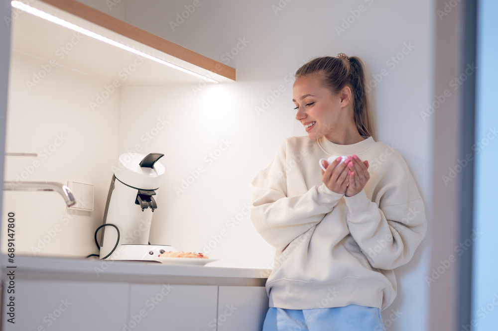 Smiling cute girl having coffee in the kitchen Smiling cute girl having coffee in the kitchen