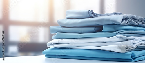 Industrial laundry providing a cleaning and ironing service for hotels clinics and companies with stacks of clean folded sheets and fabrics and an industrial iron Copy space image Place for add photo