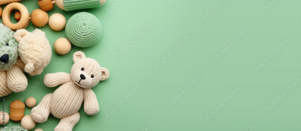 Eco friendly handmade baby toys on a mint background including wooden rattles a crocheted teddy bear and teething beads Copy space image Place for adding text or design - obrazy, fototapety, plakaty 