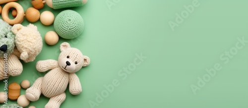 Eco friendly handmade baby toys on a mint background including wooden rattles a crocheted teddy bear and teething beads Copy space image Place for adding text or design photo