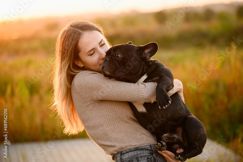 Woman holds in her arms, kisses a dog, looks at him lovingly,at sunset.The concept of friendship,trust,love, childfree photo