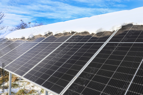 Photovoltaic panels in winter. Snow lies on their surface.