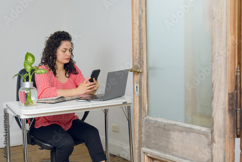young business woman sitting in her office working watching mobile