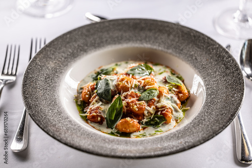 Gnocchi pomodoro with mascarpone, cream, basil and parmesan, in a stylish plate on a restaurant table
