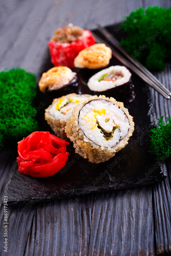 Sushi roll with salmon, smoked eel, avocado, cream cheese on black background. Sushi menu. Japanese food. Sushi roll with salmon, smoked eel, avocado, cream cheese on black background. Sushi menu. Japanese food.