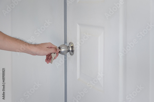 Man hand use key opening the white door. A man unlocking the door with a key.