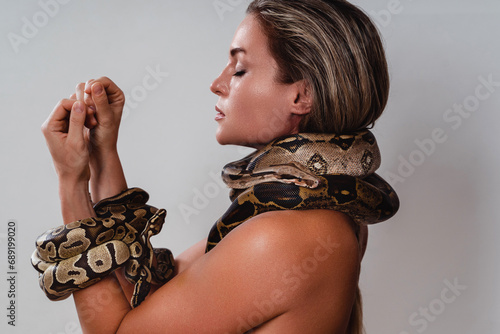 Beautiful woman with python snakes elegantly slithering over her neck and wrists