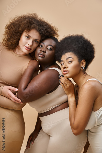 diverse multiracial body positive women in underwear smiling on beige backdrop, plus size beauty
