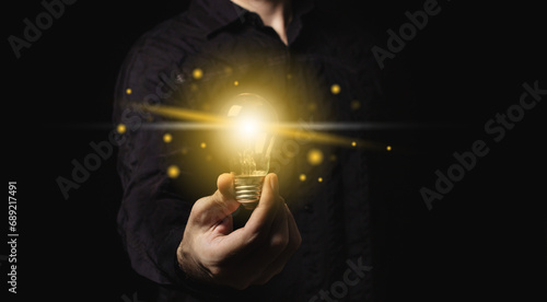 Man holding a light bulb in his hand, idea of creativity and inspiration concept of sustainable business development. Successful innovation ideas and inspiration ideas.	
