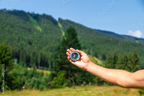A man in the mountains holds a compass in her hands. Selective focus.