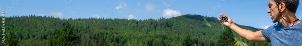 A man in the mountains holds a compass in her hands. Selective focus.