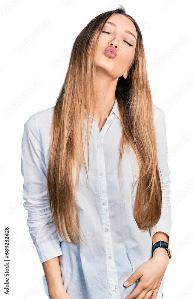 Beautiful caucasian woman wearing casual white shirt looking at the camera blowing a kiss on air being lovely and sexy. love expression. Beautiful caucasian woman wearing casual white shirt looking at the camera blowing a kiss on air being lovely and sexy. love expression.