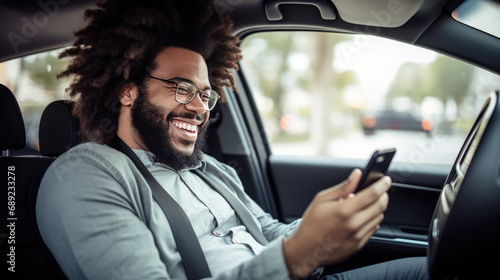 Man smiling joyfully while looking at his phone in his car. © HelenP