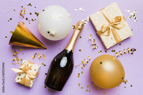 Flat lay composition of Champagne bottle gift box ribbons and confetti on colored background. Flat lay, top view holiday concept