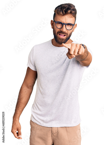 Young hispanic man wearing casual clothes and glasses pointing displeased and frustrated to the camera, angry and furious with you