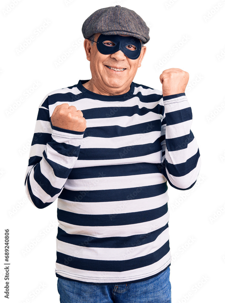 Senior handsome man wearing burglar mask and t-shirt celebrating surprised and amazed for success with arms raised and eyes closed. winner concept. Senior handsome man wearing burglar mask and t-shirt celebrating surprised and amazed for success with arms raised and eyes closed. winner concept.