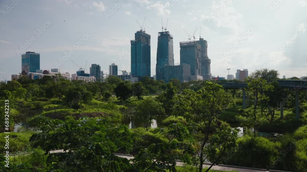 Beautiful view from the city park through the trees on the modern architecture of downtown with skyscrapers in Bangkok. Summer cityscape Beautiful view from the city park through the trees on the modern architecture of downtown with skyscrapers in Bangkok. Summer cityscape
