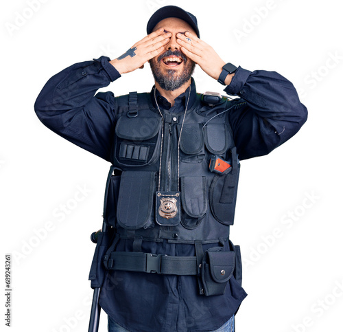 Young handsome man wearing police uniform covering eyes with hands smiling cheerful and funny. blind concept.