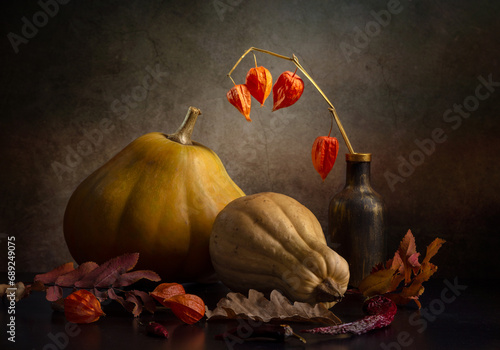 Fotografija Still life with two pumpkins and dry autumn leaves on a dark background