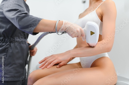 Young woman making body hair removal laser depilation in beauty center photo