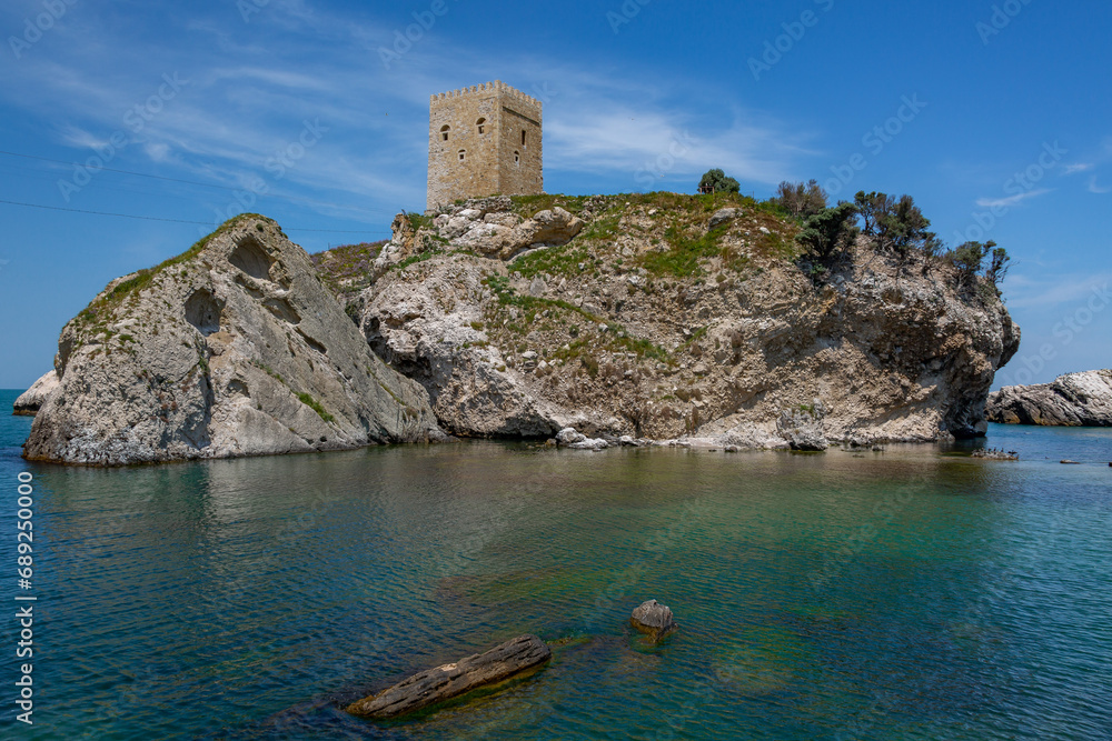 Rocky island with an old tower on top against a blue sky
