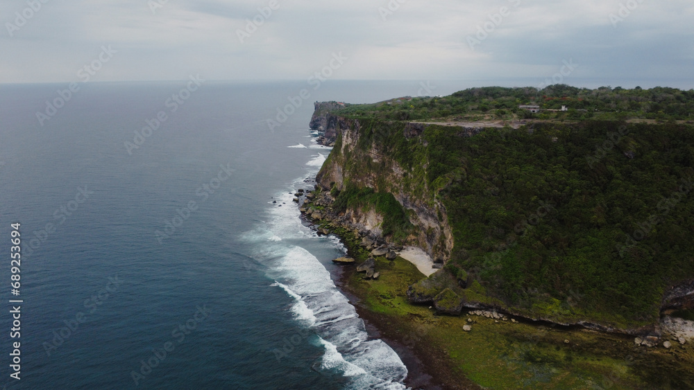 A scenic aerial top view of ocean waves hitting the rocky cliff at Wedding Cake Rock beach in Sydney