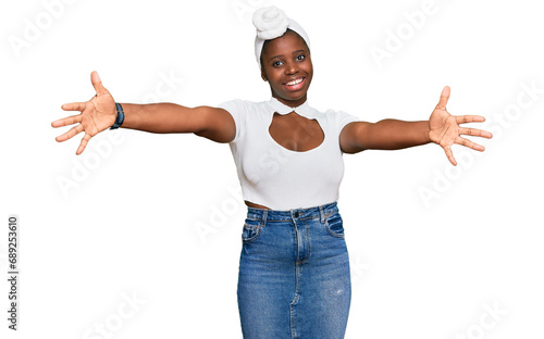 Young african woman with turban wearing hair turban over isolated background looking at the camera smiling with open arms for hug. cheerful expression embracing happiness. photo