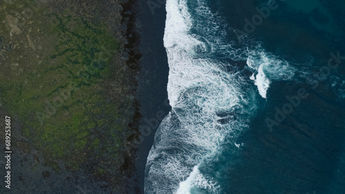 Dark sea surface aerial view. Top view blue water ocean waves with white foaming waves crashing on beach background. Amazing sea waves nature background