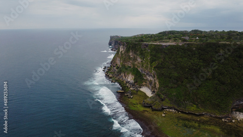 A scenic aerial top view of ocean waves hitting the rocky cliff at Wedding Cake Rock beach in Sydney
