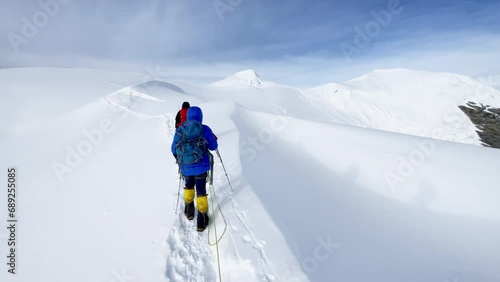 Last steps before Mera peak summit 6476m rope team dressed mountaineering clothes, boots with crampons ascending steep snowy slope. Himalaya mountains 4K handheld camera footage. photo