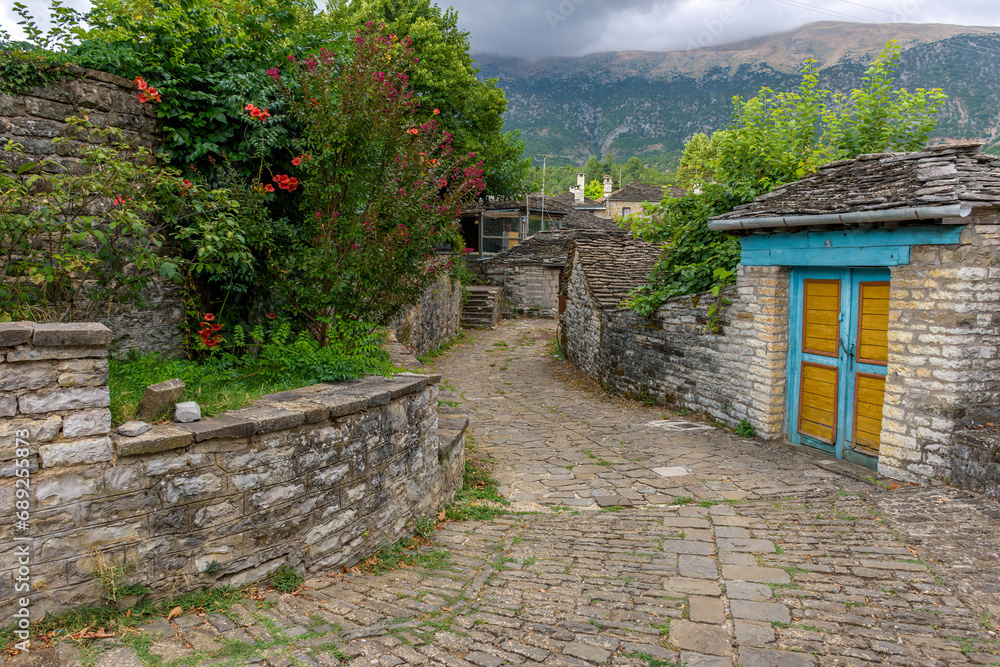 Τraditional architecture with a narrow street and stone buildings in the picturesque village of papigo , zagori Greece Τraditional architecture with a narrow street and stone buildings in the picturesque village of papigo , zagori Greece