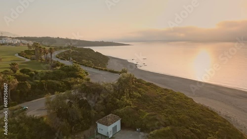 Establishing aerial view of couple driving  convertible sport car on the costal at beautiful sunset. Happy young couple on summer vacation traveling at the seaside 