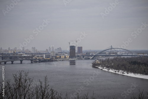 KYIV, UKRAINE - DECEMBER 6, 2023: A SNOW-COVERED CITY WITH A WONDERFUL VIEW OF THE DNIPRO RIVER AND PODIL. FOG COVERS THE CITY AND MINUS TEMPERATURE OUTSIDE © HannaBg