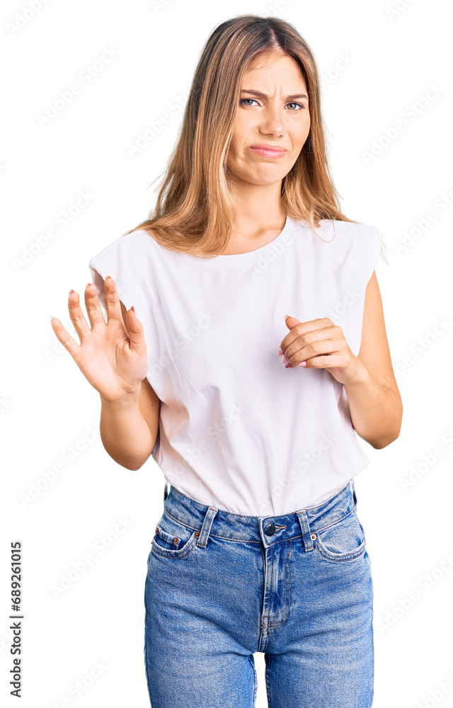 Beautiful caucasian woman with blonde hair wearing casual white tshirt disgusted expression, displeased and fearful doing disgust face because aversion reaction. with hands raised Beautiful caucasian woman with blonde hair wearing casual white tshirt disgusted expression, displeased and fearful doing disgust face because aversion reaction. with hands raised
