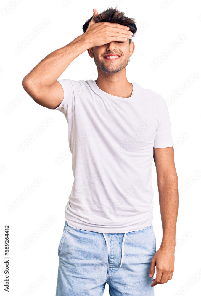 Young hispanic man wearing casual clothes smiling and laughing with hand on face covering eyes for surprise. blind concept. Young hispanic man wearing casual clothes smiling and laughing with hand on face covering eyes for surprise. blind concept.