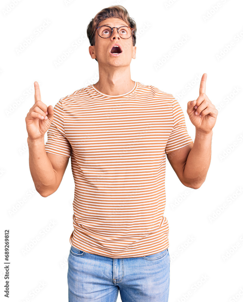 Young handsome man wearing casual clothes and glasses amazed and surprised looking up and pointing with fingers and raised arms. Young handsome man wearing casual clothes and glasses amazed and surprised looking up and pointing with fingers and raised arms.