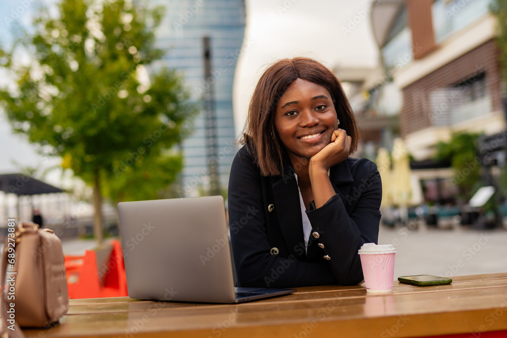 By the riverside, the formally dressed businesswoman of color works on her laptop, checking her email and savoring a cup of coffee. By the riverside, the formally dressed businesswoman of color works on her laptop, checking her email and savoring a cup of coffee.