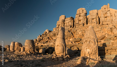 Statue heads with headless seated statues at sunrise, East Terrace, Mount Nemrut, Turkey photo