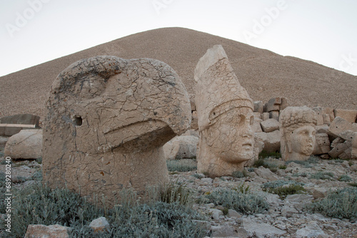 close up of the head of eagle statue and Antiochus with the tumulus of the royal tomb in the background, Mount Nemrut, Turkey