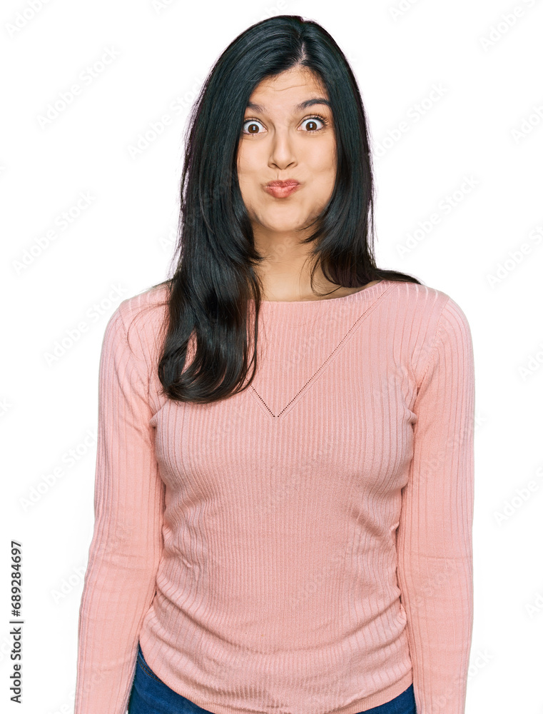 Young hispanic woman wearing casual clothes puffing cheeks with funny face. mouth inflated with air, crazy expression. Young hispanic woman wearing casual clothes puffing cheeks with funny face. mouth inflated with air, crazy expression.