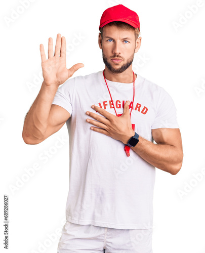 Young caucasian man wearing lifeguard t shirt holding whistle swearing with hand on chest and open palm, making a loyalty promise oath